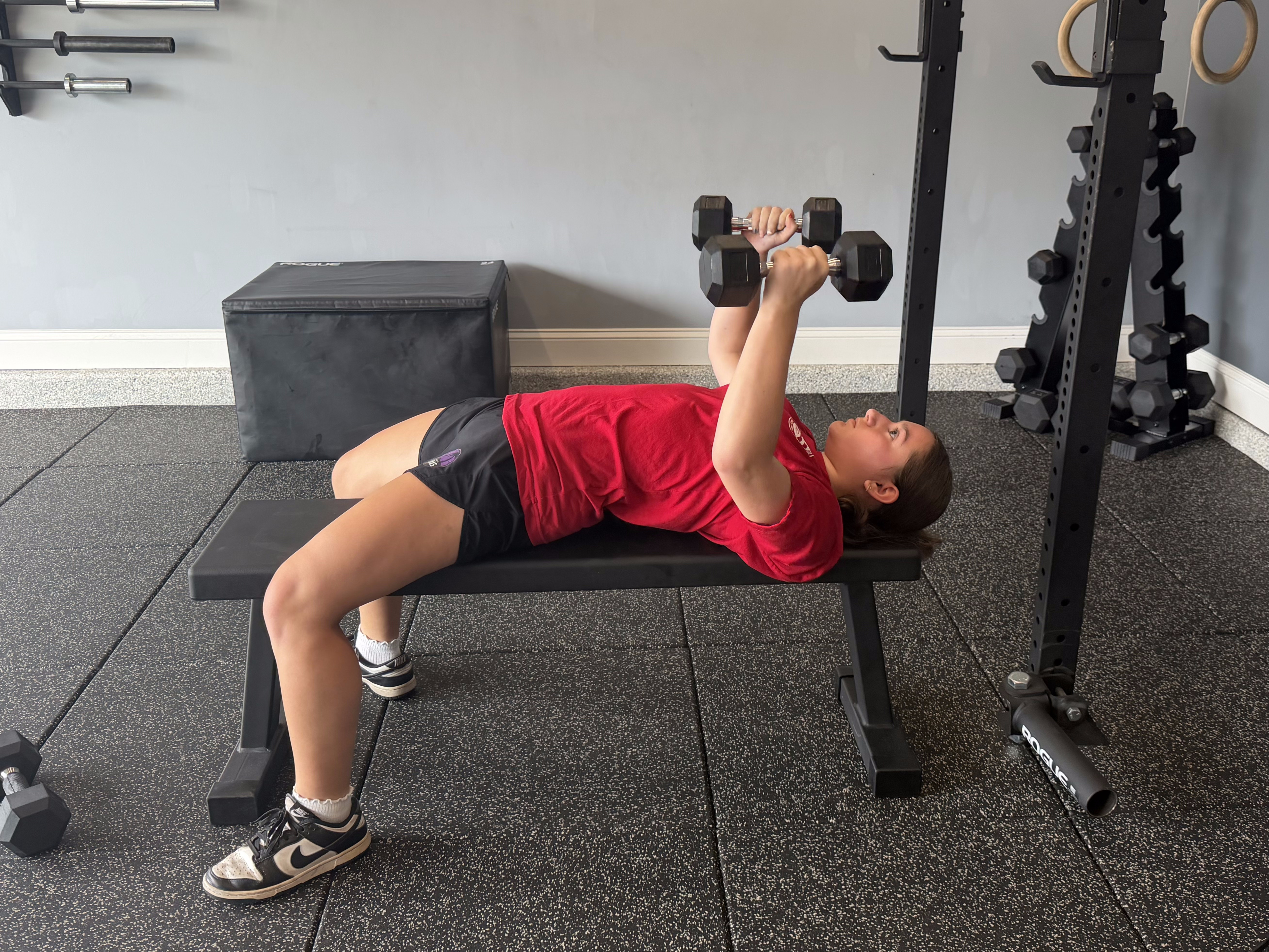 Client performing a dumbbell bench press during training
